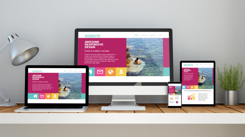 A computer, laptop, smartphone and tablet on a desktop workspace with  responsive website on screen. 3d rendering. All screen graphics are made up.